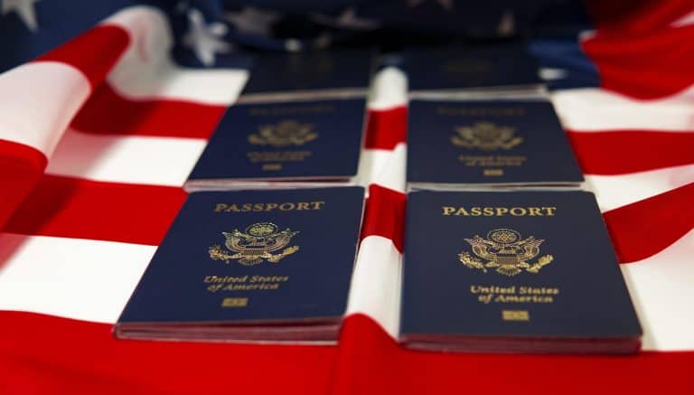 Visa Renewal USA: Effortless Steps for Immigrant Help 24 U.S. passports on an American flag-themed background, symbolizing travel and immigration.